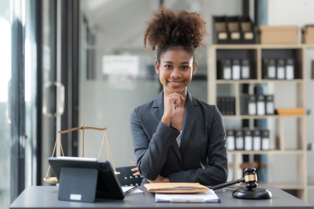 Confident young woman lawyer sitting in office and looking at camera.